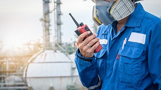 Worker in blue protective suit with respirator holding a radio during hazard communication training