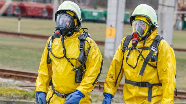 Two workers in yellow protective suits wearing respirators during respiratory protection training