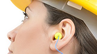Worker wearing yellow earplug and hard hat during hearing conservation training