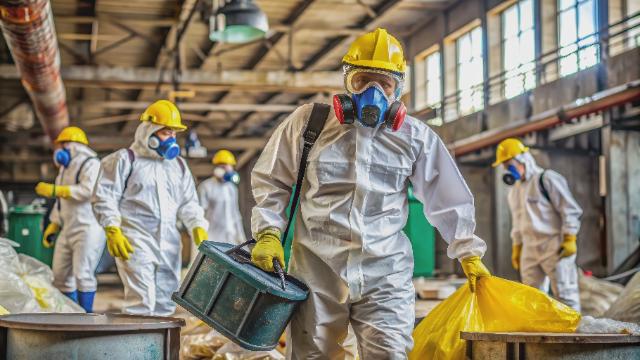 Workers in protective hazmat suits at a worksite during asbestos awareness training
