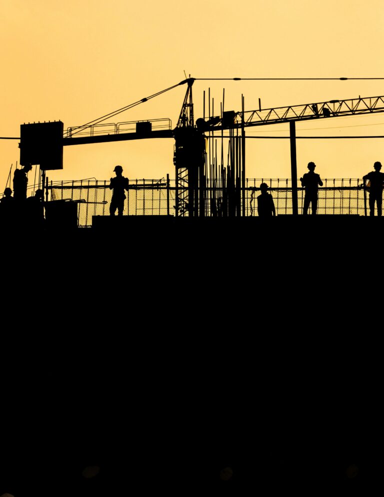 Silhouetted construction workers at sunset