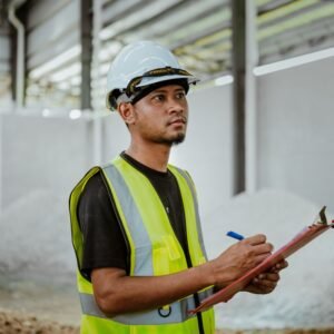 Safety inspector in hard hat and vest completing a workplace inspection checklist for a California IIPP