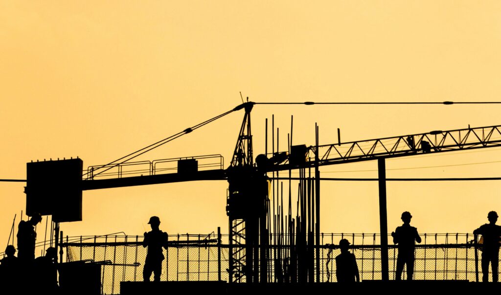 Silhouetted construction workers at sunset